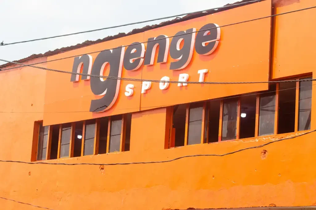 Façade d’un bâtiment Ngenge Sport, peint en orange avec un grand logo en 3D sur le mur.